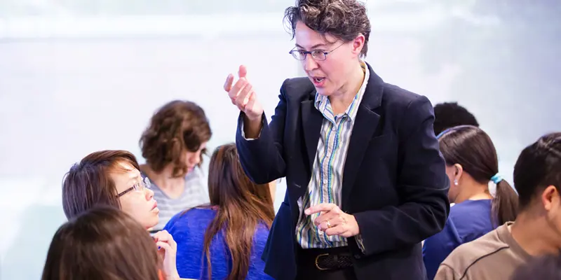 Professor Jennifer Cromley explaining a topic to a student discussion group during class.